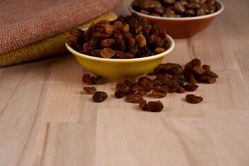 Dried raisins in a bowl on a wooden background stock images. Raisins sultanas still life photo images. Raisins on the table stock images. Raisins on a wooden background with copy space for text