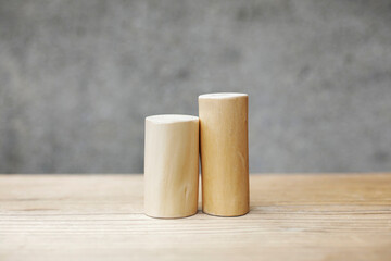 Thin and short barkless wooden log blocks on wooden table. Barkless cedar log set lined up closely together in order of height on wooden background. 