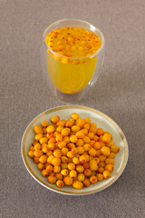 Vertical photo yellow sea buckthorn berries in a dish with hot drink with berries in a glass