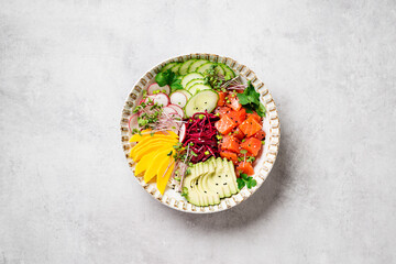 Poke bowl with fresh marinated salmon and variegated vegetables, green onions and microgreens. Light gray background. top view