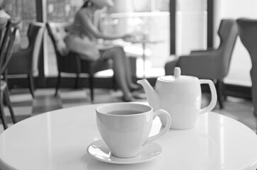 Monochrome porcelain teacup and pot on a round table in a cafe