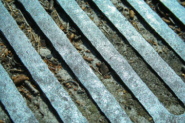 Stainless steel grate of a clogged stormwater drain in Melbourne Australia. Drain cover blocked by sand, dirt, fallen leaves and rubbish in selective focus.