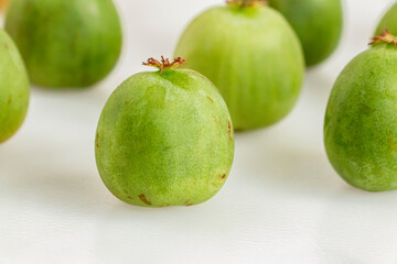 Kiwiberry in selective focus against rows of neatly lined kiwiberries. Also known as baby kiwi fruit, hardy kiwi or actinidia arguta. New Zealand exotic fruit.