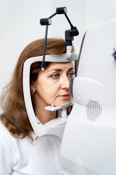 Woman has eyes examined on a slit lamp. Modern equipment for eye sigth check up in clinic. Closeup.