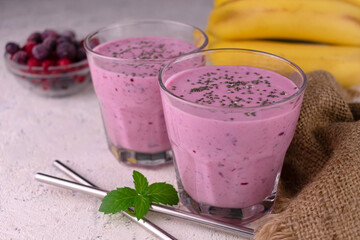 Two glasses of berry banana smoothie with chia seeds on white
background.