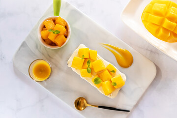 Creamy cheese pie and ripe mango with juicy mango sauce. Sweet and sour dessert sauce. Top view.