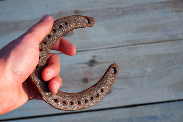 Fototapeta premium A man's hand holds an old horseshoe. Natural wood background. Wood texture. Place for your text.