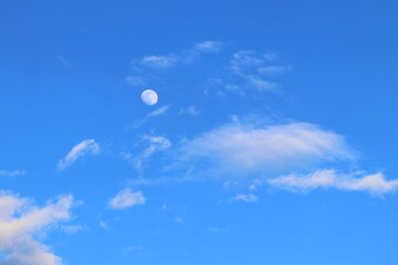 Naklejka na ściany i meble Moon in the blue sky among the clouds. 