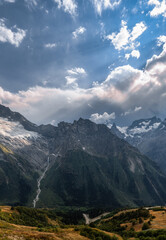 Epic mountain landscape with sun rays from behind the clouds. Vertical panorama in high resolution