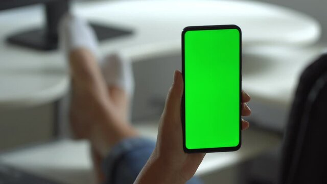 Handheld Camera: Point of View of Woman at Modern Room Sitting on a Chair Using Phone With Green Mock-up Screen Chroma Key Surfing Internet Watching Content Videos Blogs