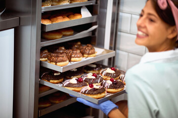 A young small business female owner in a candy workshop fills the closet with delicious handmade...