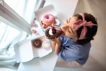 A young girl in a pastry shop eating delicious donuts with a pleasure. Pastry shop, dessert, sweet