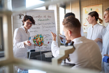 Young cheerful chemical students discuss a lesson in the university laboratory. Science, chemistry, lab, people