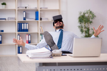 Young male employee wearing virtual glasses at workplace