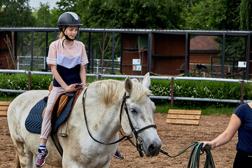 Beautiful teenage girl in a helmet learning to ride a horse.