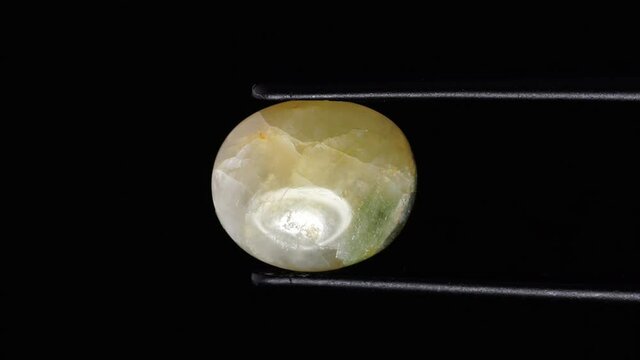 natural moss quartz gemstone in tweezer on the turning table
