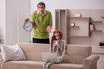 Young man with female skeleton in time management concept