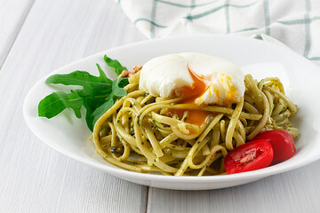 Pasta with arugula pesto and poached egg, on a white background, horizontal, no people,