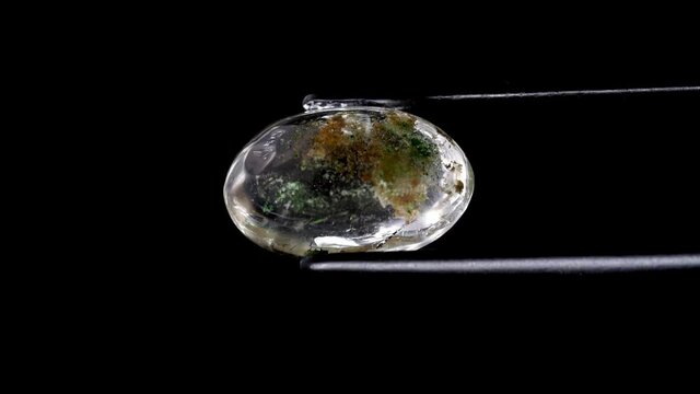 natural moss quartz gemstone in tweezer on the turning table
