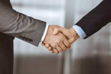 Business people in office suits standing and shaking hands, close-up. Business communication concept. Handshake and marketing