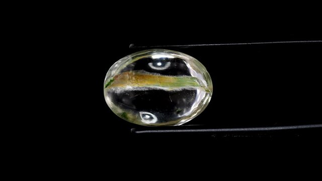 natural moss quartz gemstone in tweezer on the turning table