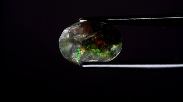 natural moss quartz gemstone in tweezer on the turning table