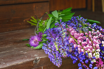 Purple - pink lupine bouquet collected in summer lies on a wooden background