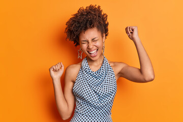 Isolated shot of beautiful African American woman has fun laughs from joy dressed in fashionable...