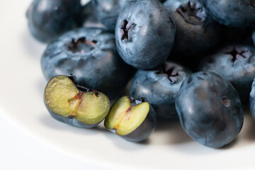 Halved blueberry in selective focus against a heap of blueberries. Close-up of an antioxidant superfood.