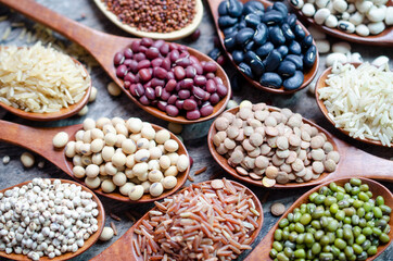 Closed up dry organic soybean seeds in wodoen spoon with lentils, red and black bean, mung bean, rice, quinoa, millet, and black eye pea
