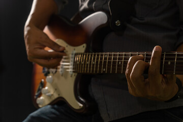 Fototapeta premium Hands of the man playing electric guitar. Low key photo.