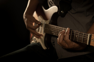 Obraz na płótnie Canvas Hands of the man playing electric guitar. Low key photo.
