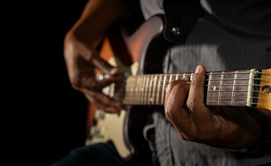 Fototapeta na wymiar Hands of the man playing electric guitar. Low key photo.