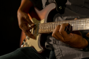 Fototapeta na wymiar Hands of the man playing electric guitar. Low key photo.