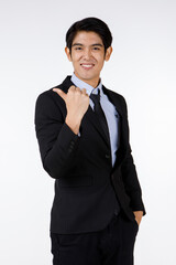 Obraz na płótnie Canvas Portrait shot of Asian young happy confident white collar businessman in black stylish modern formal suit standing smiling look at camera showing thumb up admiring in front of white background