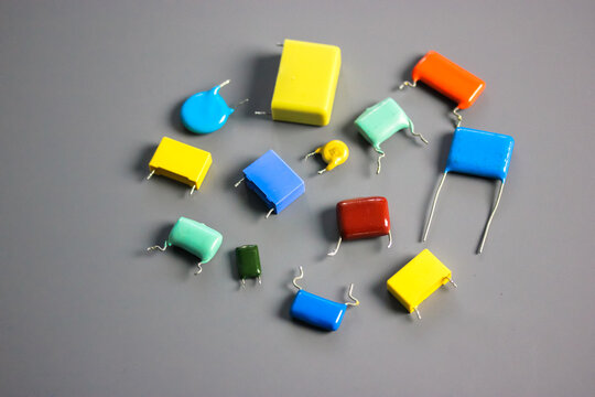 Subminiature polypropylene multicolored film capacitors on gray background flatly. Vintage electronic parts. Resistors and capacitors different size and color. HiFi Audio parts. Radio components.