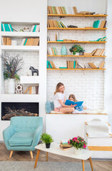 Happy caucasian mom with her daughter reading a book and smiling