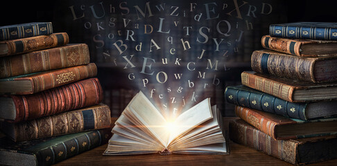 Old book with flying letters and magic light on the background of the bookshelf in the library....