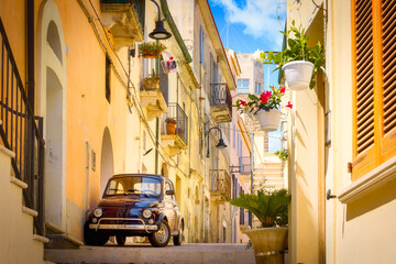 Narrow street in the old town, with colorful houses, cobblestones and an old 500 car parked,  Termoli, Italy
