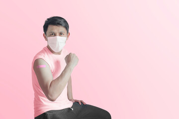 Asian man using adhesive bandage plaster and clench his fist after vaccination in the hospital. For protect coronavirus (covid-19).