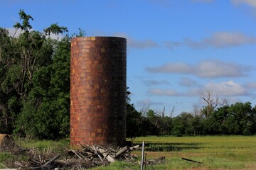 Farm Silo in a farm field with green grass, blue sky and white clouds west of Nickerson Kansas USA. © Stockphotoman
