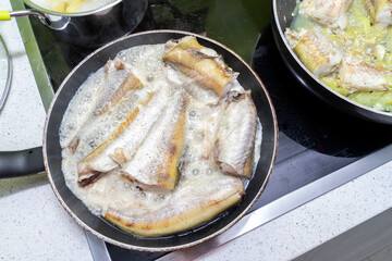 fish is cooked in two pans on an induction hob