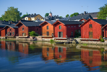 Fototapeta na wymiar Old wooden warehouses on the banks of the Porvoonjoki river in the light of the evening sun on a summer evening. Porvoo, Finland