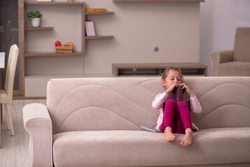 Obraz premium Small girl reading book at home
