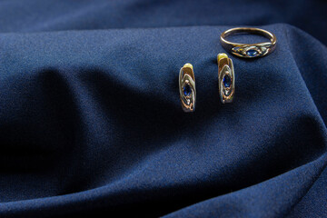  Pair of platinum earring with sapphire gemstone on blue satin background. Luxury female jewelry, close-up