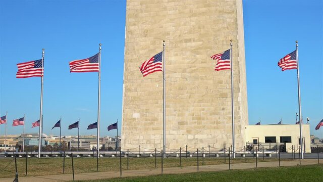 Flags of the United States near washington monument waving over blue sky, Washington DC