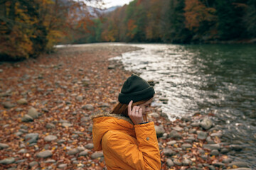 woman in autumn clothes on nature near the river walk the mountains