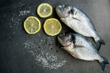 Uncooked fish on kitchen table. Close up photo of fresh dorado with sea salt. Gray textured background. Healthy eating concept.