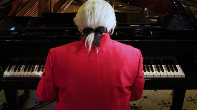 A man pianist, wearing clothes of the 18th century nobility, playing a rondo by Wolfgang Amadeus Mozart on a piano.