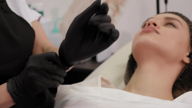 Close-up of a cosmetologist putting on gloves before working with a client.